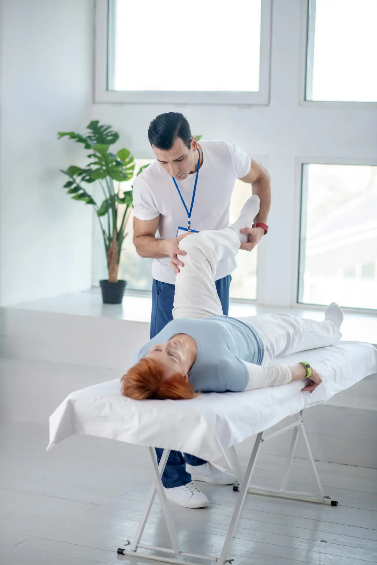 Physiotherapist assisting patient with leg stretch